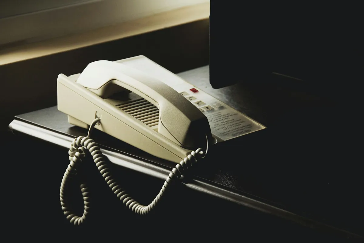 Teléfono fijo blanco sobre el mostrador de una oficina